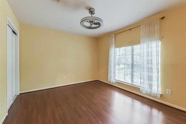 empty room with baseboards, ceiling fan, and dark wood-style floors