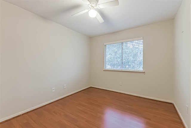 spare room with baseboards, ceiling fan, and wood finished floors
