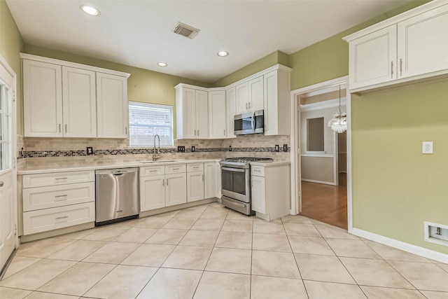 kitchen featuring a sink, light countertops, stainless steel appliances, decorative backsplash, and visible vents