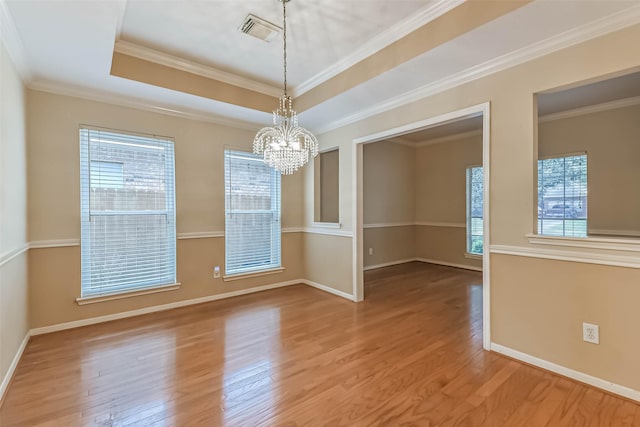 unfurnished dining area featuring an inviting chandelier, baseboards, wood finished floors, a tray ceiling, and visible vents