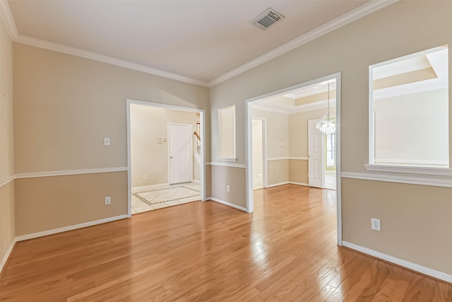 unfurnished room with crown molding, a notable chandelier, light wood finished floors, baseboards, and visible vents