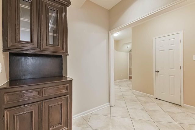 corridor featuring light tile patterned flooring and baseboards