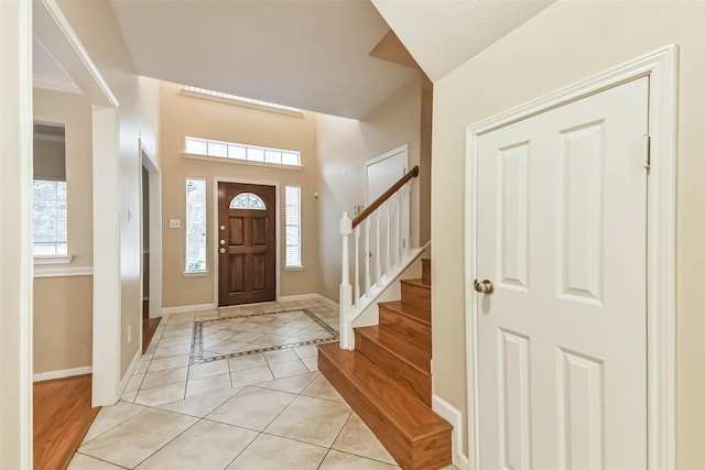 foyer with stairway, baseboards, and light tile patterned flooring