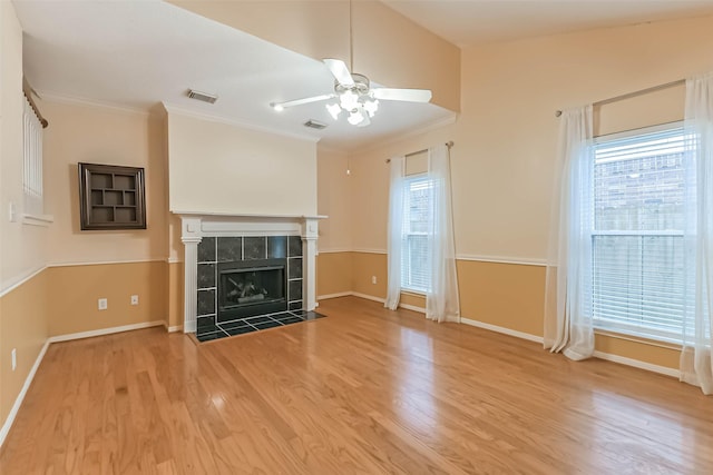 unfurnished living room with plenty of natural light, ceiling fan, a tile fireplace, and visible vents