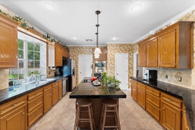 kitchen with a kitchen breakfast bar, appliances with stainless steel finishes, a sink, ornamental molding, and wallpapered walls