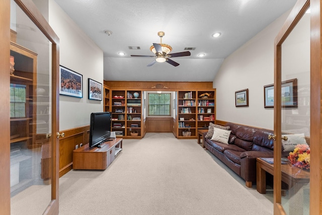 living area featuring visible vents, a ceiling fan, carpet, and wainscoting