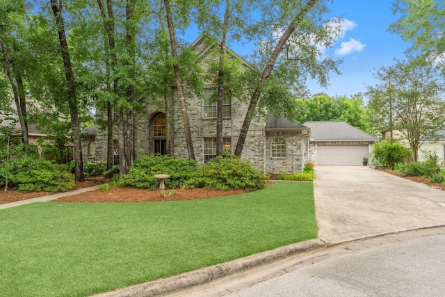 view of front of house featuring an attached garage, a front lawn, driveway, and stone siding