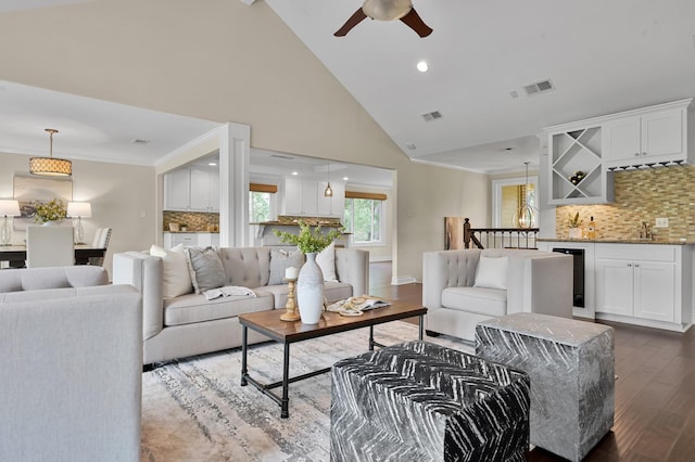 living area with wet bar, visible vents, wood finished floors, and ceiling fan