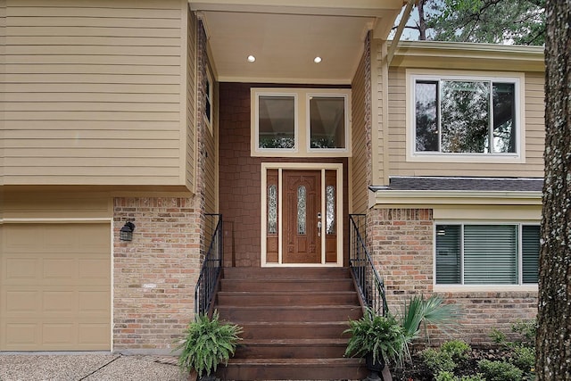 view of exterior entry with a garage and brick siding