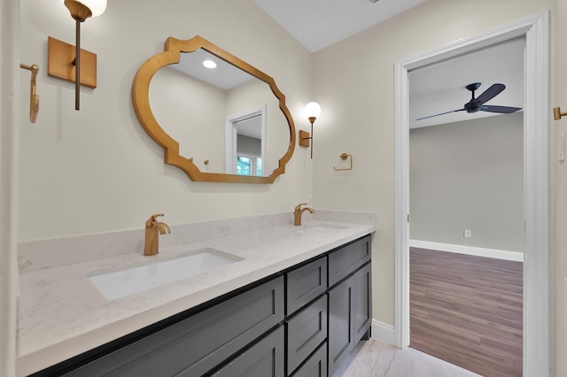 full bathroom with a ceiling fan, baseboards, double vanity, and a sink