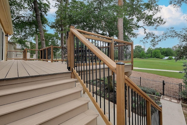wooden deck featuring view of golf course, stairs, and fence