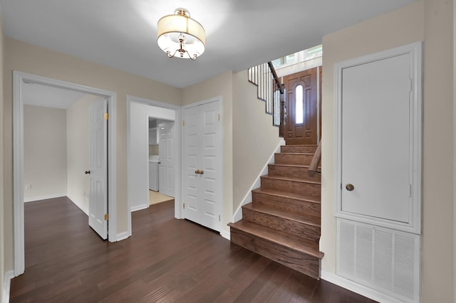 staircase featuring wood finished floors, visible vents, baseboards, a chandelier, and washer / clothes dryer