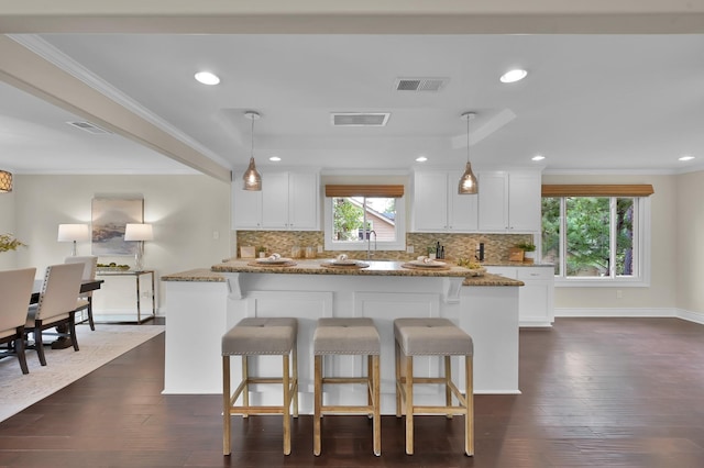 kitchen with a kitchen breakfast bar, backsplash, and visible vents