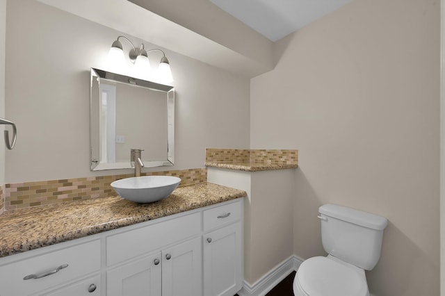 bathroom with vanity, toilet, decorative backsplash, and baseboards