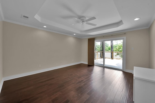 spare room with a tray ceiling, visible vents, dark wood-style flooring, and a ceiling fan