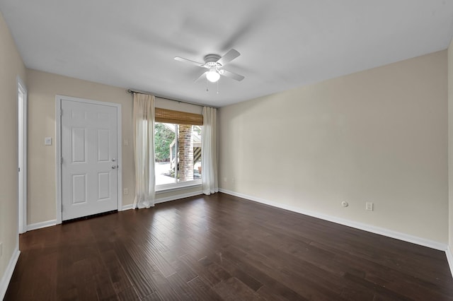 empty room with baseboards, ceiling fan, and dark wood-style floors