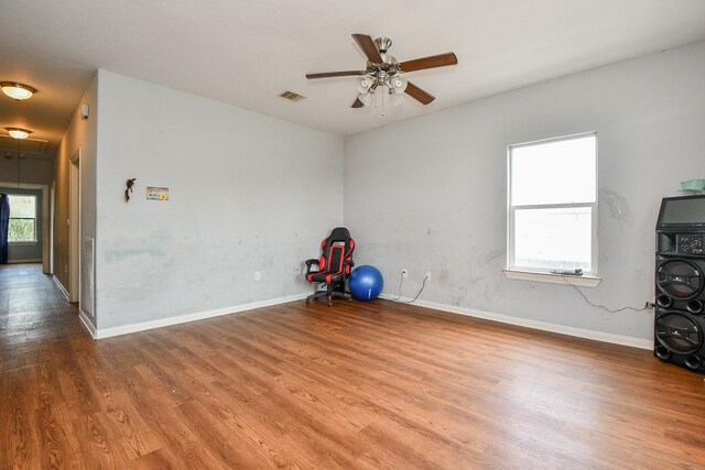 interior space featuring baseboards, ceiling fan, wood finished floors, and visible vents