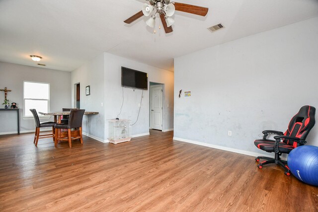 interior space with visible vents, a ceiling fan, baseboards, and wood finished floors