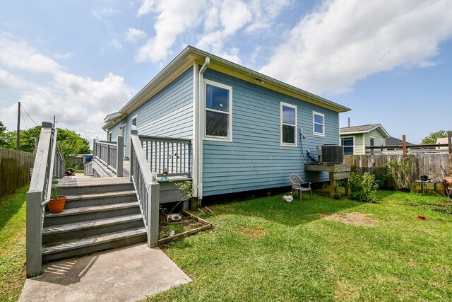 rear view of house featuring central air condition unit, a yard, and fence