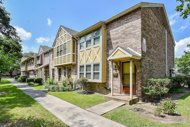 view of property featuring a residential view, a front lawn, and brick siding