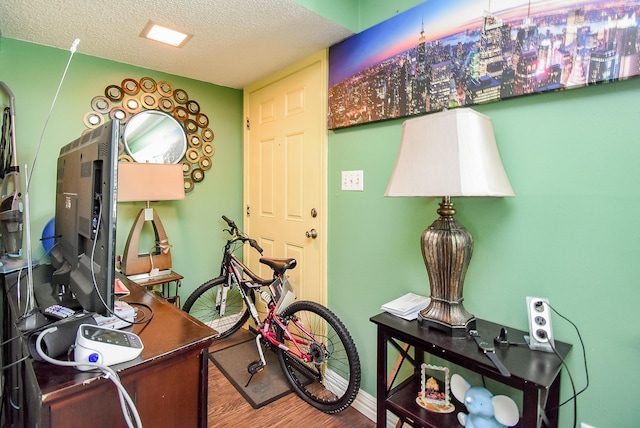 office area with a textured ceiling, baseboards, and wood finished floors