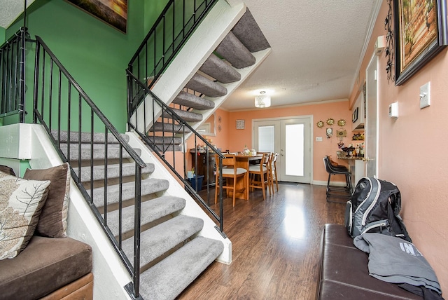 staircase with crown molding, baseboards, a textured ceiling, and wood finished floors