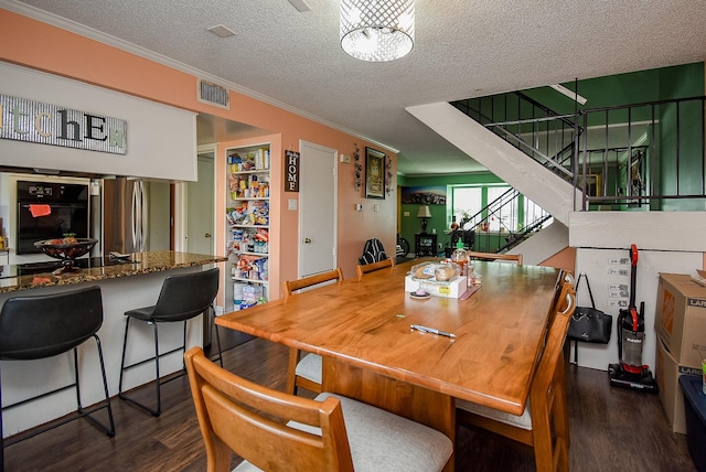 dining room featuring visible vents, a textured ceiling, and dark wood finished floors