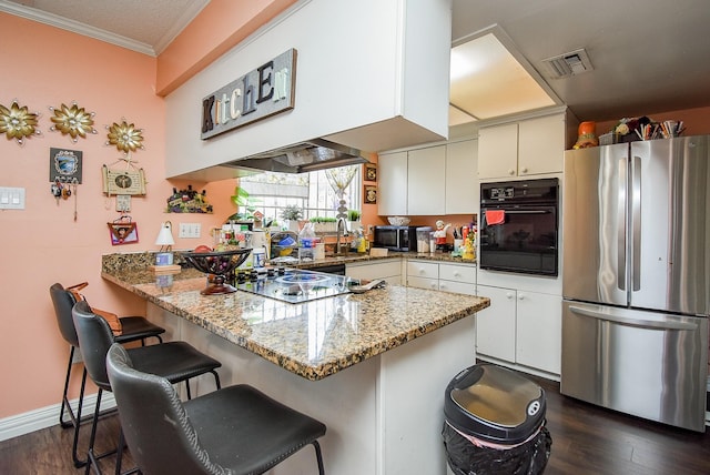 kitchen featuring a breakfast bar area, visible vents, dark wood finished floors, black appliances, and a peninsula