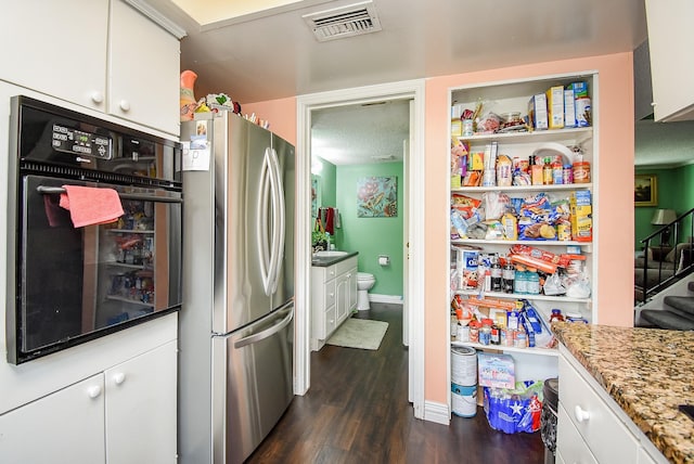 kitchen with visible vents, freestanding refrigerator, wall oven, white cabinetry, and dark wood finished floors