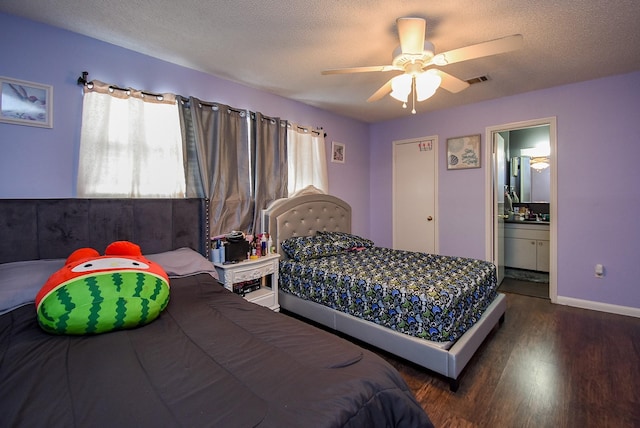 bedroom with baseboards, a textured ceiling, wood finished floors, and ensuite bathroom
