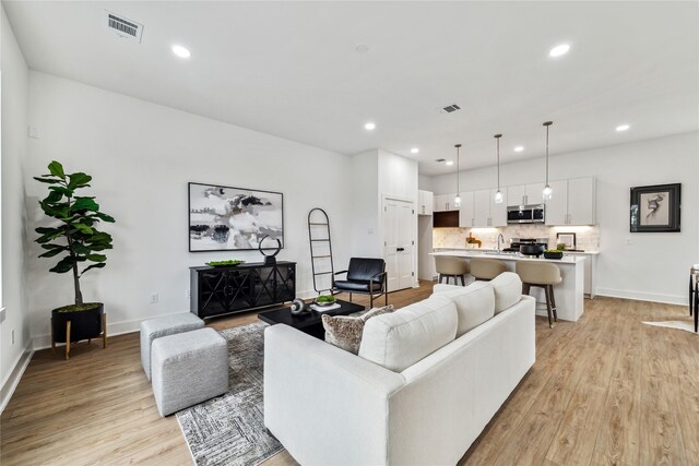 living area with light wood-style floors, baseboards, recessed lighting, and visible vents