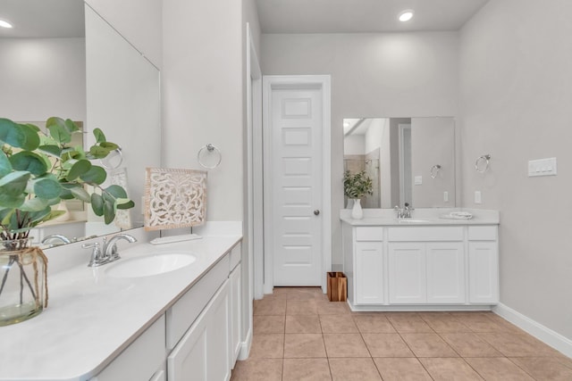 full bath featuring baseboards, a sink, tile patterned floors, and two vanities