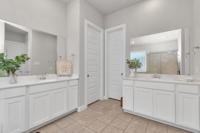 bathroom with a sink, a stall shower, tile patterned floors, and two vanities