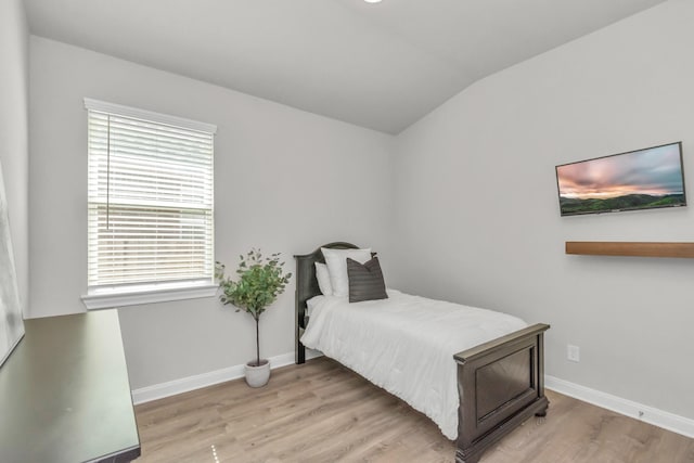 bedroom featuring baseboards, lofted ceiling, and light wood finished floors
