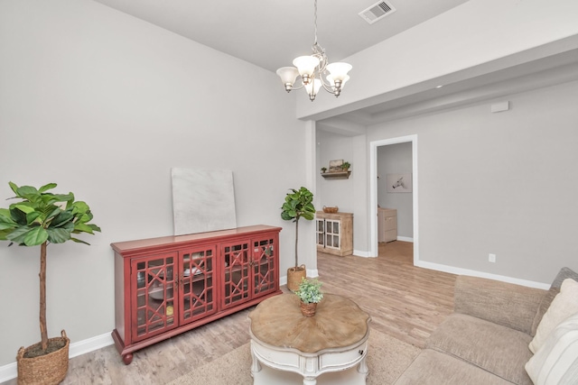 living room featuring baseboards, a notable chandelier, visible vents, and wood finished floors
