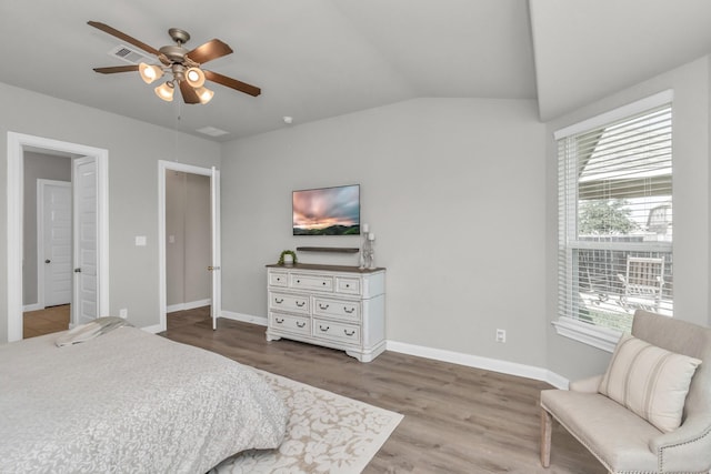 bedroom featuring a ceiling fan, visible vents, wood finished floors, baseboards, and lofted ceiling