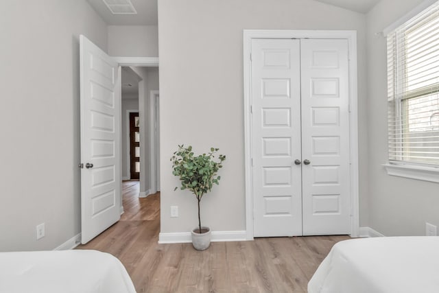 bedroom featuring visible vents, a closet, baseboards, multiple windows, and light wood-type flooring