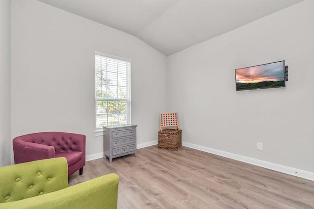 living area with baseboards, wood finished floors, and vaulted ceiling