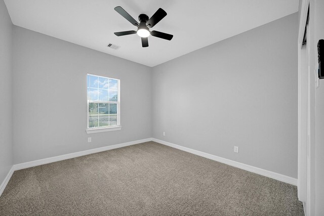 carpeted empty room featuring visible vents, a ceiling fan, and baseboards