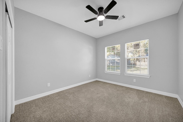 carpeted spare room with baseboards, visible vents, and ceiling fan