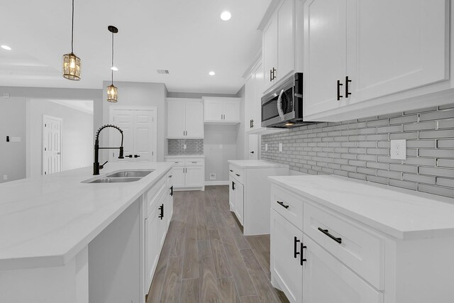 kitchen with recessed lighting, a sink, stainless steel microwave, and backsplash