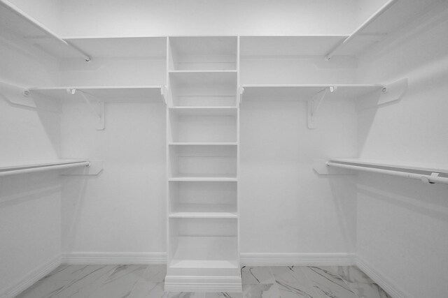 walk in closet featuring marble finish floor