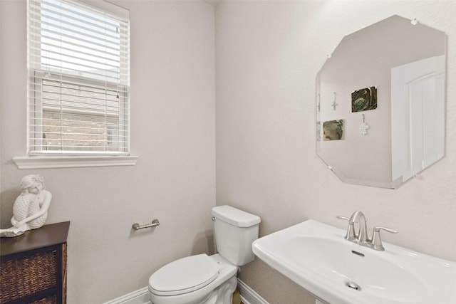 bathroom featuring baseboards, a sink, and toilet