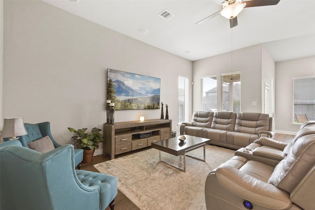 living area with light wood-type flooring, baseboards, ceiling fan, and visible vents