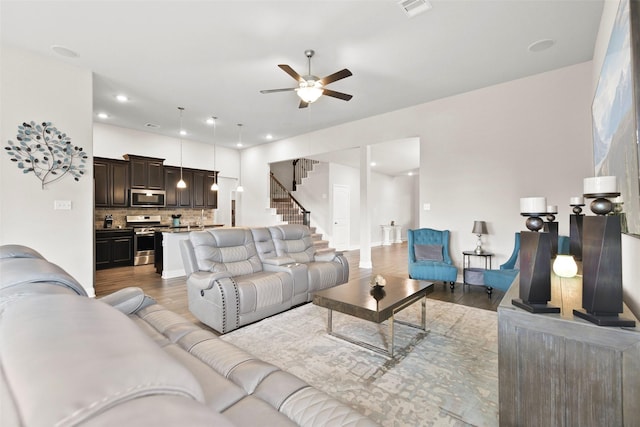 living area with stairway, a ceiling fan, wood finished floors, and visible vents