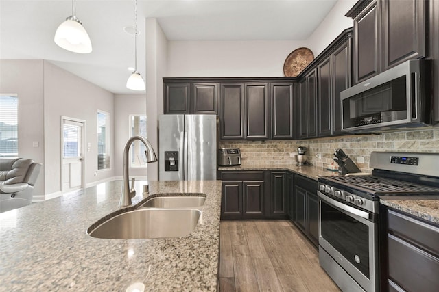 kitchen featuring light stone countertops, appliances with stainless steel finishes, a sink, and tasteful backsplash