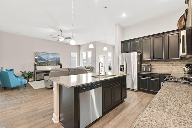 kitchen featuring decorative backsplash, ceiling fan, light wood-type flooring, a sink, and stainless steel appliances