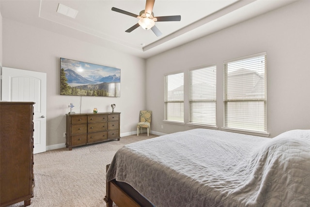 carpeted bedroom with baseboards, ceiling fan, and a raised ceiling