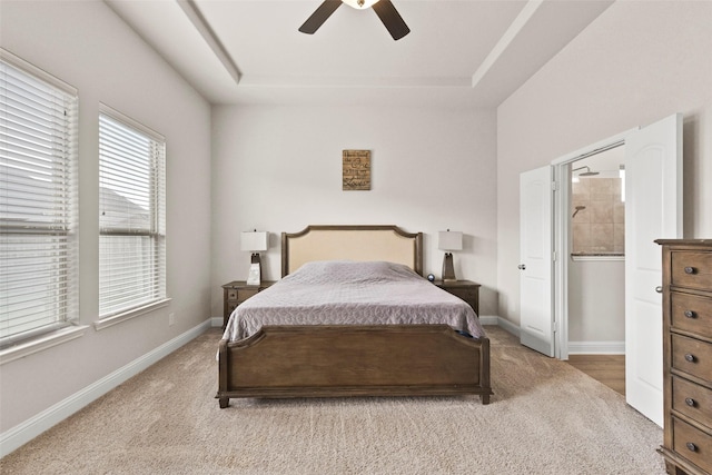 bedroom featuring baseboards, ceiling fan, a tray ceiling, and light carpet
