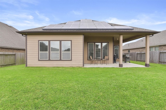 back of house featuring a fenced backyard, a patio, a yard, and solar panels